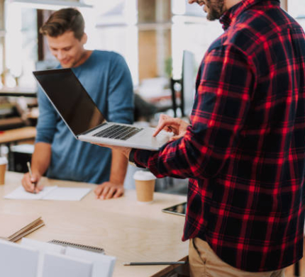 Cheerful young male colleagues standing in the office while working in one team